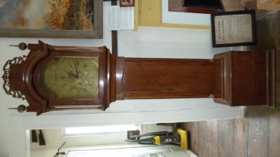 A Burnap clock that stands about 80 inches tall, handmade with a wood case and brass face and clockworks. On face says: Daniel Burnap, E. Windsor.